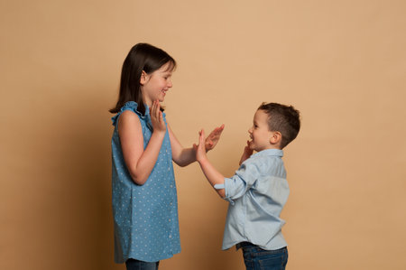 girl 9-12 years old and a boy 5-7 years old communicate on a beige background, communication between peersの写真素材
