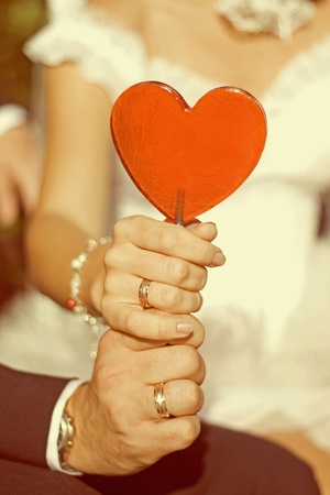 Hands with wedding rings, the bride and groom holding a red heartの写真素材
