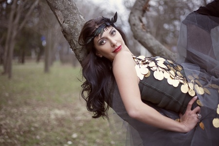 Sexy woman in fashionable clothing lying on a tree branch