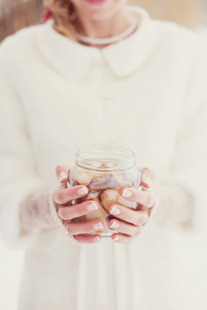 bride in winter park with a beautiful manicure, with a jar of cookies in handの写真素材