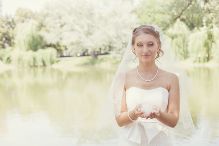 bride in a white dress with a wedding bouquet at the lakeの写真素材