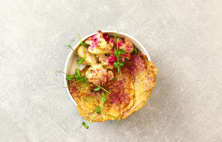 Healthy food delivery concept. Beef schnitzel with cauliflower in an eco paper container on a gray...