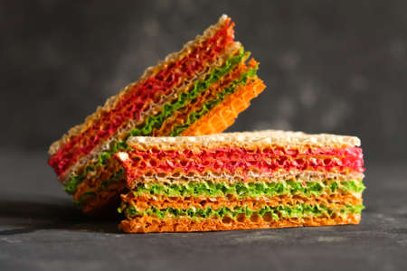 Colorful pieces of waffle cake with condensed milk on a dark background. close up.の写真素材