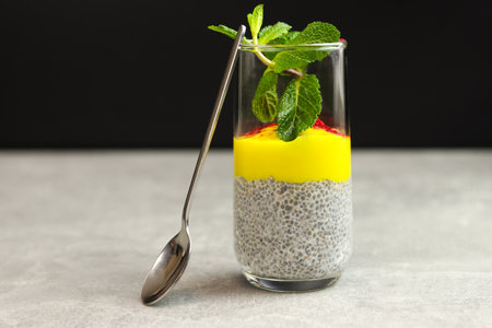 Chia pudding with mango puree in transparent glass isolated on gray black background.の写真素材