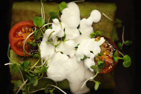 Green thin spinash pancakes or crepes stuffed chicken meat and vegetables with sour cream in eco...