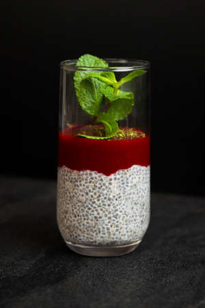 Chia seed pudding with strawberry and mint in a glass on a dark backgroundの写真素材