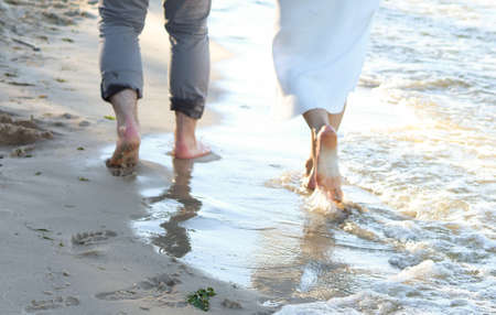 Couple walking barefoot on the beach in the evening. Close-up.の写真素材