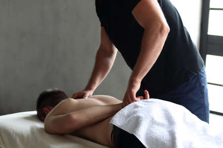 Therapist doing back sports massage to male patient athlete at studioの写真素材