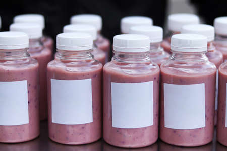 Bottles with tasty berry smoothie on table, closeup