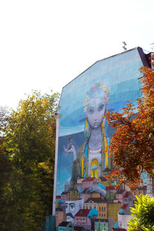 Kyiv, Ukraine - August 30, 2019: Part of an artistically painted house, skyscraper, ukrainian girl with wreath of flowers on her head on blue house wall, mural painting.のeditorial素材