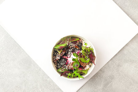 Salad of lettuce, beet and chicken liver with fresh radicchio and sesame seeds in a takeaway round container topped with yoghurt sauce on gray background. Healthy food delivery.の写真素材