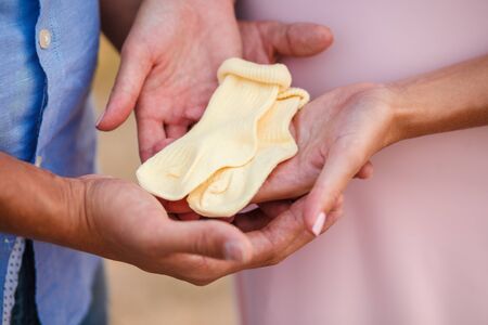 Male and female hands hold baby booties close-upの写真素材