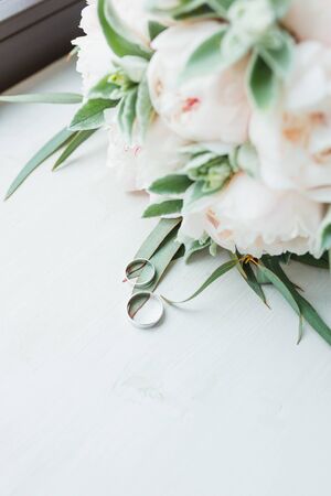 Bridal bouquet of peonies and rings on the windowsill. Close up.の写真素材