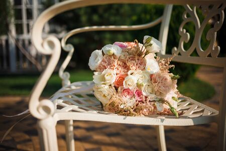 Bridal bouquet of roses and rings on chair on the natural background. Close up.の写真素材