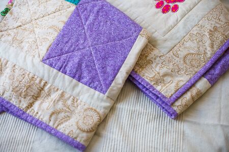 A handmade patchwork quilt repeating square pattern. Close up.