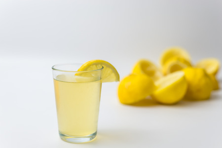 Squeezed lemon peels after making a fresh juice with glass cup on white backgroundの写真素材