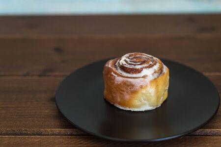 Sweet cinnamon bun roll swirl over the black plateの写真素材