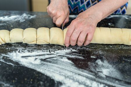 mother preparing a dough for cinnamon rolls at the kitchenの写真素材