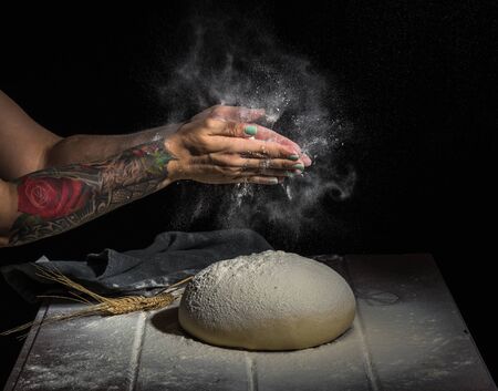 Risen  yeast dough for bread or pizza on a floured surface with woman hands sprinkled the flour , 45...