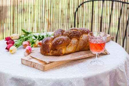 Challah bread on round table served with Amber wine in a glass  , with flowers on background , Shabbat timeの写真素材