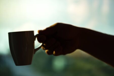 Blurred hand with cup of coffeeの写真素材