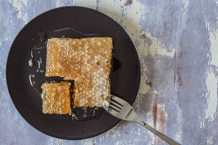 Honeycomb on black plate, on grey background, top view, flat lay with copy space