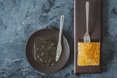 Honeycomb on brown plate on black background, top view, flat lay