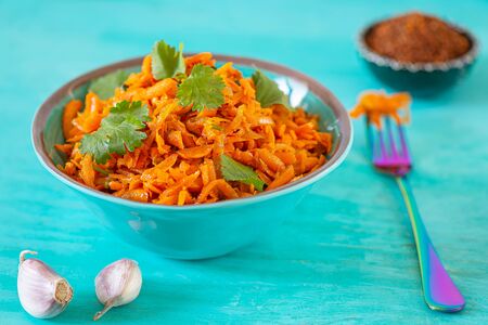 Spicy Korean carrot salad in a turquoise bowl on a turquoise wooden background. Healthy Korean foodの写真素材