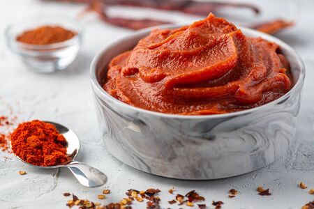 Traditional home made Korean red sause Gochujang can also be named Harissa Moroccan red hot chilli sause. Healthy spicy, vegetarian appetizer or snack with roasted red pepper dip, front view, close upの写真素材