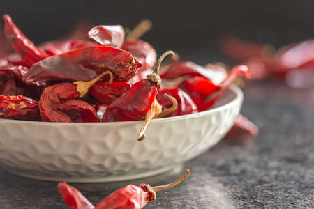Dried red chili or chilli cayenne pepper in grey bawl on black marble background, close upの写真素材