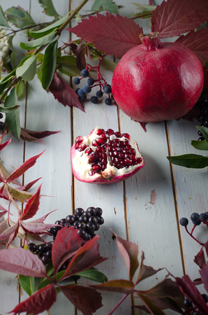 pomegranate and leaves on a white wooden backgroundの写真素材