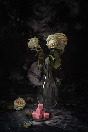 There are three faded roses on the table, darkの写真素材