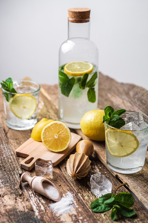 Two glasses of lemonade with with lemon slices, mint and ice on old wooden planks.の写真素材