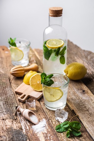 Two glasses of lemonade with with lemon slices, mint and ice on old wooden planks. Close upの写真素材