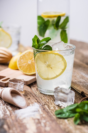 Two glasses of lemonade with with lemon slices, mint and ice on old wooden planks. Close upの写真素材