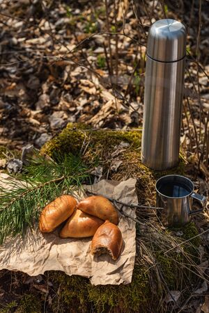 Fresh homemade meat patty cakes, and steel cup on stump in the forest.の写真素材