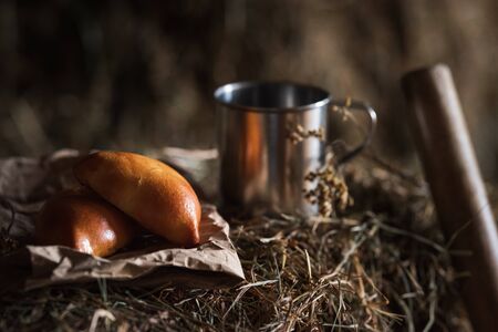 Fresh homemade meat patty cakes and steel cup on hayloft. Picnic. Close upの写真素材