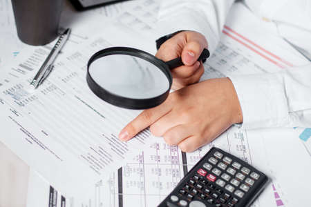 Businessman using magnifying to review balance sheet annual. Concept of Internal audit, Auditing...