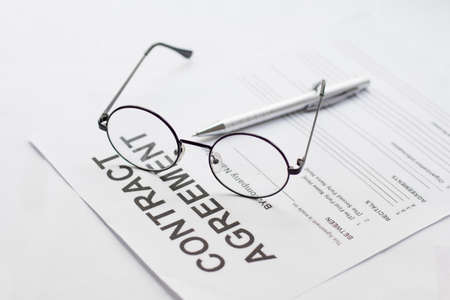 Signing contract with glasses and a pen nearby