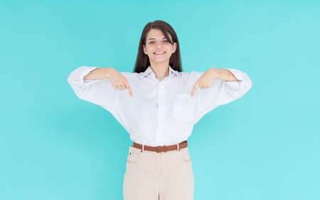 Beautiful young european woman point down to blank space isolated on blue background