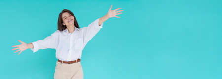 Smiling young brunette woman girl in white shirt posing isolated on pastel blue wall background...