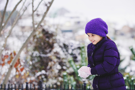 Beautiful young girl in the violet clothes playing with snow outdoor.の写真素材