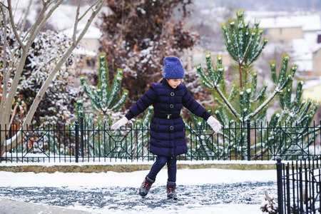 Beautiful young girl in the violet clothes playing with snow outdoor.の写真素材