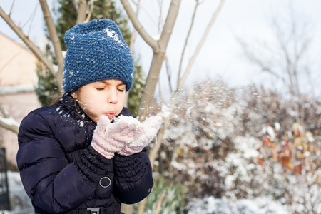 Beautiful young girl in the violet clothes playing with snow outdoor.の写真素材
