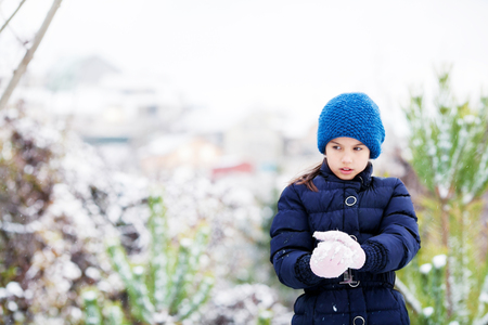 Beautiful young girl in the blue clothes playing with snow outdoor.の写真素材