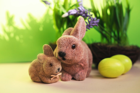 Couple Easter bunny toys and color eggs on the spring background. Rabbits family. Easter holiday...