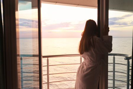 Back view of young woman enjoying the sea side view from her hotel.の写真素材