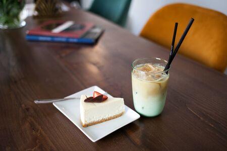 Tasty delicious cake with strawberry and Cold Coffee Frappe with ice. Cafe interior on the background.の写真素材