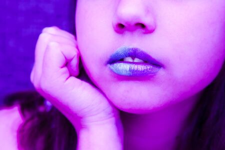 Girl in neon light with blue lipsteak on her lips. Glamur modern visage with trendy glowing make-up, colorful make up. Glitter Vivid neon makeup.の写真素材