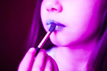Girl in neon light with blue lipsteak on her lips. Glamur modern visage with trendy glowing make-up, colorful make up. Glitter Vivid neon makeup.の写真素材